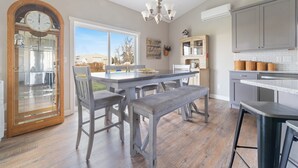 Une cuisine avec une porte en bois, une table à manger avec des chaises, un banc et un lustre.