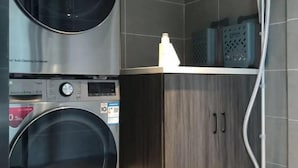 Un espace buanderie comprenant un lave-linge, un sèche-linge et une étagère avec des paniers.