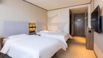 A hotel room with two beds, a flat-screen TV, and a walk-in closet.