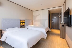 Una habitación de hotel con dos camas, un televisor de pantalla plana y un vestidor.