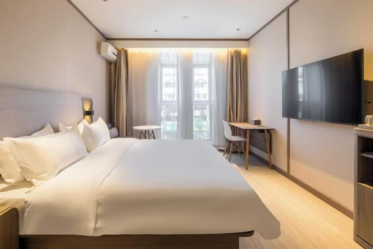 A hotel room with a large bed, a TV, a small table, and a chair.