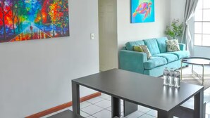 Un soggiorno moderno con un divano color petrolio, un tavolino da caffè e due quadri alle pareti.