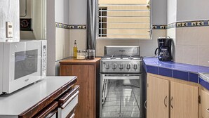 Una cucina con un piano cottura Whirlpool in acciaio inossidabile, un forno a microonde e una macchina da caffè.