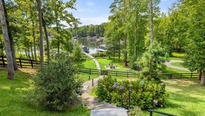A lakeside property with a pathway leading to a dock, surrounded by lush greenery and a wooden fence. - Lakefront Lake Anna, Dock, Views, Deck, Movies (Mineral)