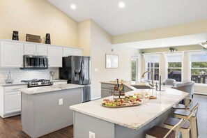 A modern kitchen with a central island, stainless steel appliances, and a dining area with a view.