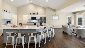 A modern kitchen with a central island, bar stools, and a dining area with chairs. - Lakefront Lake Anna, Dock, Views, Deck, Movies (Mineral)