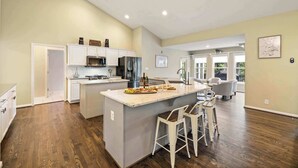 A spacious kitchen with a large island, white cabinetry, and a dining area with bar stools. - Lakefront Lake Anna, Dock, Views, Deck, Movies (Mineral)