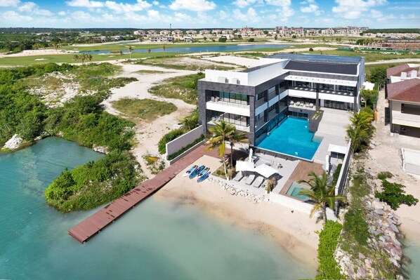 Ein modernes Hotel mit großem Pool, Strandbereich und Blick auf die umliegende Landschaft.