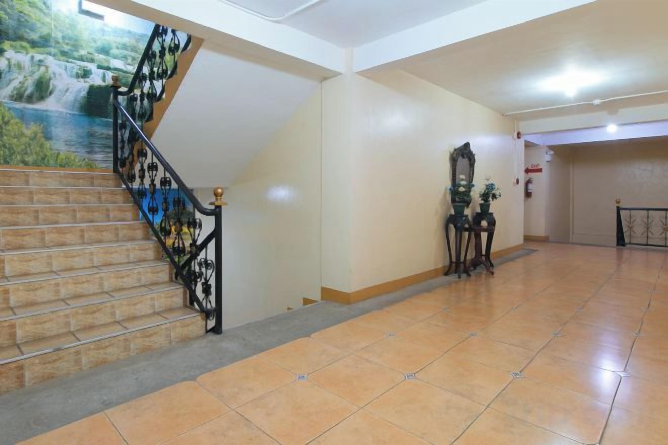 Una escalera con barandilla, una pared con un mural y un piso de baldosas.