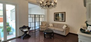 Un soggiorno con divano, una panca, un tavolino da caffè, un lampadario e un quadro appeso al muro.