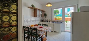 Una cucina con tavolo e sedie, un frigorifero e una finestra vista esterna.