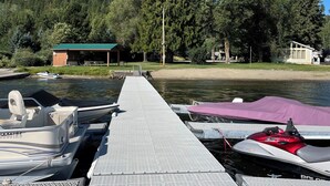 A dock with boats, a covered area, and a forested hillside.