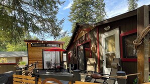 A wooden deck with a rustic cabin-style building, outdoor seating, and a large wooden planter.
