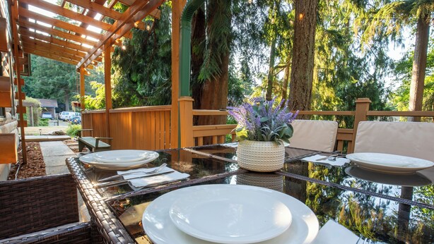 A dining area with a glass table, white plates, and wicker chairs.