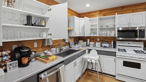 A modern kitchen with white cabinets, a coffee station, a microwave, and a stove.