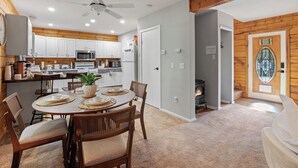 A modern kitchen with white cabinets, a microwave, and a dining area with a round table and chairs.