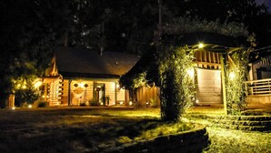 A log cabin with a well-lit entrance, a covered porch, and a garage.