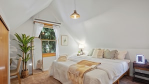 A bedroom with a bed, bedside table, lamp, and a potted plant.