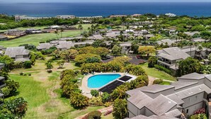 A residential area with a swimming pool surrounded by lush greenery and a view of the ocean. - 180 Degree Ocean View in Wailea! WE204 (Kihei)
