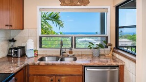 A kitchen with a view of the ocean, a blender, a toaster, a sink, and a dishwasher. - 180 Degree Ocean View in Wailea! WE204 (Kihei)
