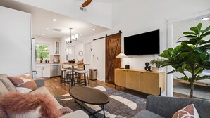Ein modernes Wohnzimmer mit einer Couch, einem Couchtisch und einem an der Wand befestigten Fernseher.
