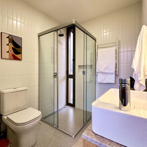 A bathroom with a glass-enclosed shower, a toilet, and a sink with a towel rack. - Clareira Cabanas (Gonçalves)