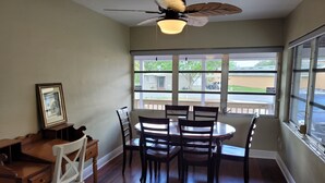A dining area with a round table, four chairs, a ceiling fan, and large windows offering a view of the outside. - Cozy Home Near I-4, Lakeland hospital, cancer center ＆ Joker Marchant Stadium (Lakeland)