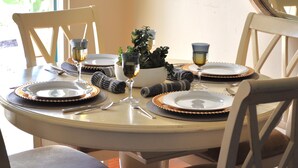 Una mesa de comedor preparada con platos, vasos y cubiertos, rodeada de sillas.