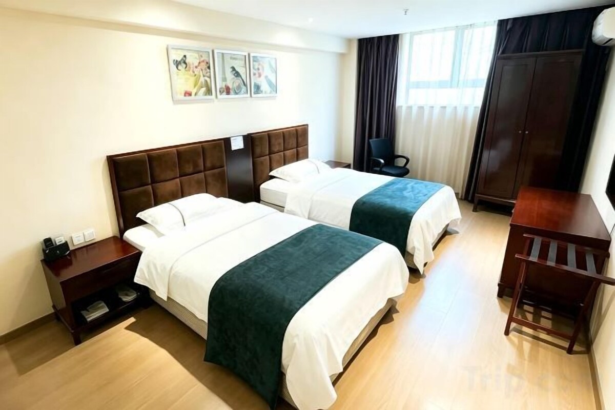A hotel room with two beds, a desk, and a chair.