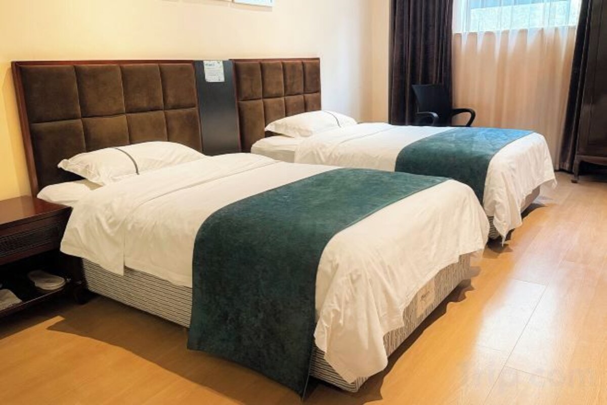 A hotel room with two beds, a nightstand, and a chair.