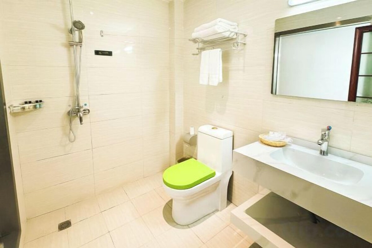 A bathroom with a shower, toilet, sink, and mirror.