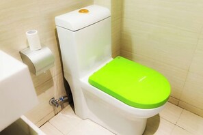 A toilet with a green seat and lid, a toilet paper holder, and a flush handle. - Dinghui Holiday Hotel (Chongqing)