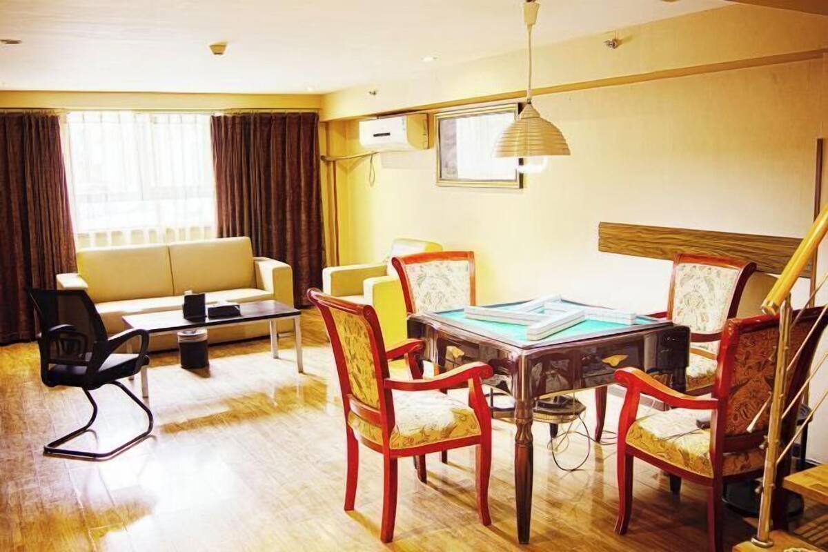 A hotel room with a dining table, chairs, a sofa, and a lamp.
