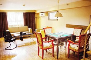 A hotel room with a dining table, chairs, a sofa, and a lamp. - Dinghui Holiday Hotel (Chongqing)