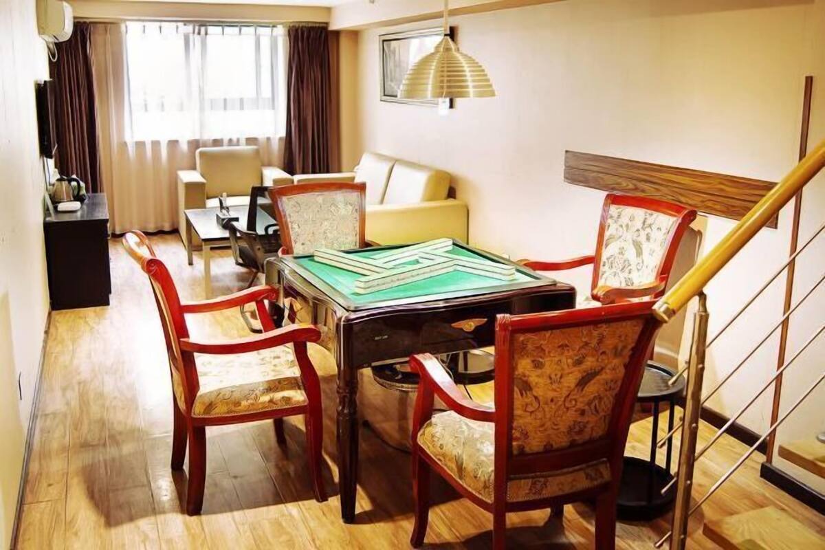 A room with a billiards table, four chairs, a sofa, a TV, and a staircase.