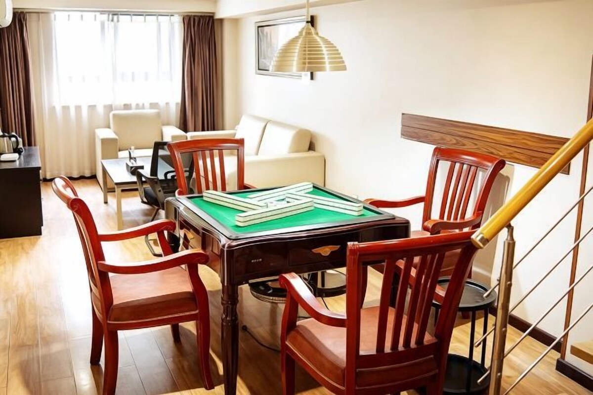 A dining area with a pool table, wooden chairs, a sofa, and a staircase.
