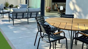 An outdoor patio with a round wooden table and black metal chairs. - Homely Basel Airport  (Saint-Louis)