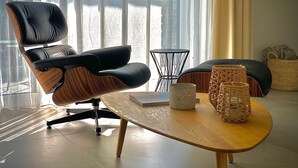 A modern living room with a leather chair, a wooden coffee table, and wicker baskets. - Homely Basel Airport  (Saint-Louis)