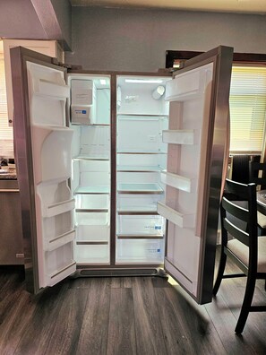 A modern kitchen with a built-in refrigerator, wooden flooring, and a dining area with a chair. - Cozy 1-bedroom apartment in lovely St. Louis with WiFi, AC (St. Louis)