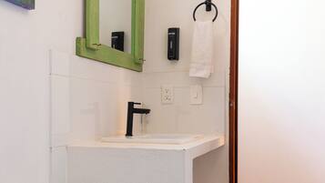A bathroom with a white toilet, a green-framed mirror, a white sink, and a towel rack.