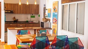 Una cocina moderna con armarios de madera, microondas y un comedor con sillas coloridas y una mesa de madera.