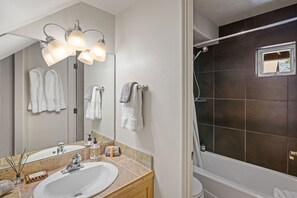 A bathroom with a sink, mirror, towel racks, and a shower area.