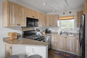 A kitchen with wooden cabinets, a stove, microwave, and a refrigerator.