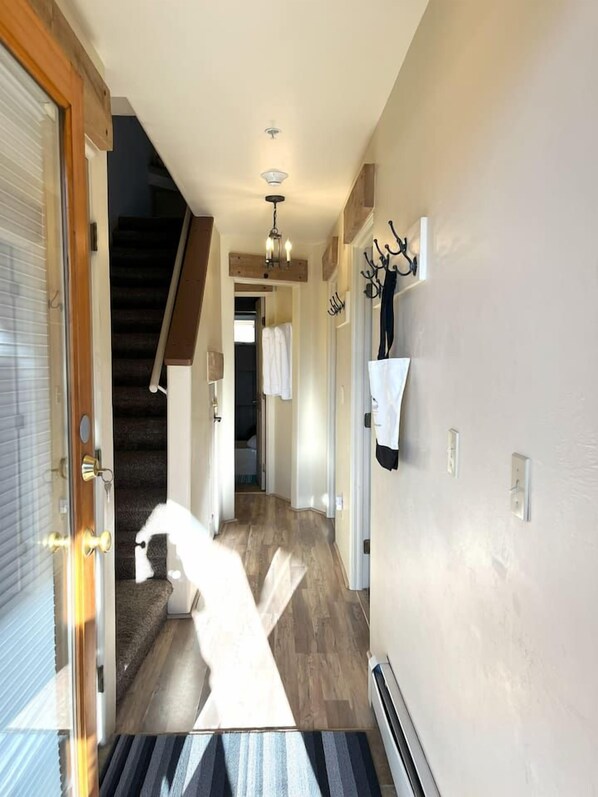 A hallway with a wooden floor, a staircase, and a door leading to a room.