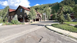 A mountain lodge with a red roof, wooden exterior, and a driveway leading to the entrance.