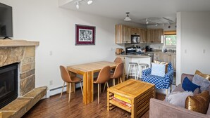 A modern living room with a fireplace, wooden dining table, and a cozy seating area.