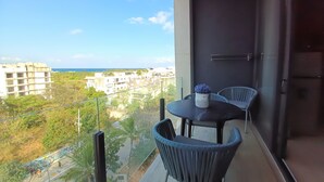 Ein Balkon mit Tisch und Stühlen, mit Blick auf eine Stadtlandschaft und ein Gewässer.