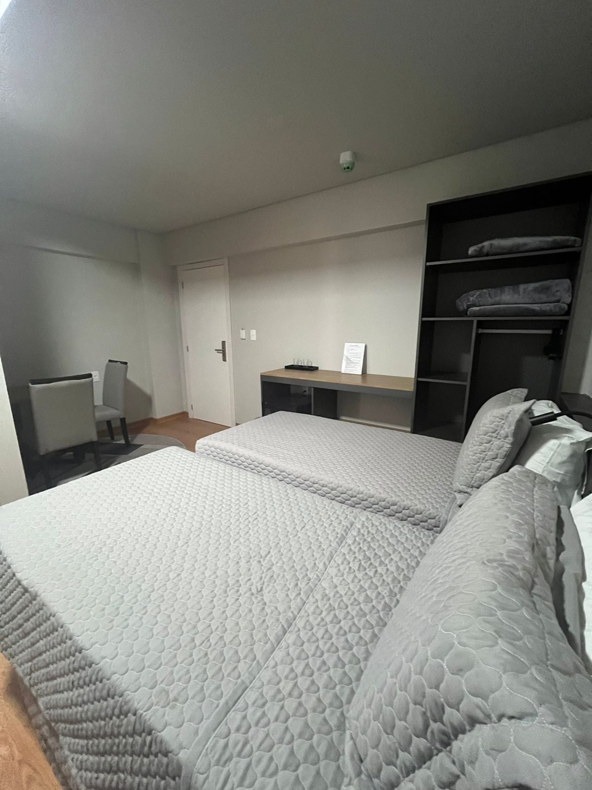 A bedroom with two beds, a desk, and a wardrobe.