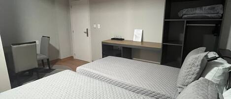 A bedroom with two beds, a desk, and a wardrobe.