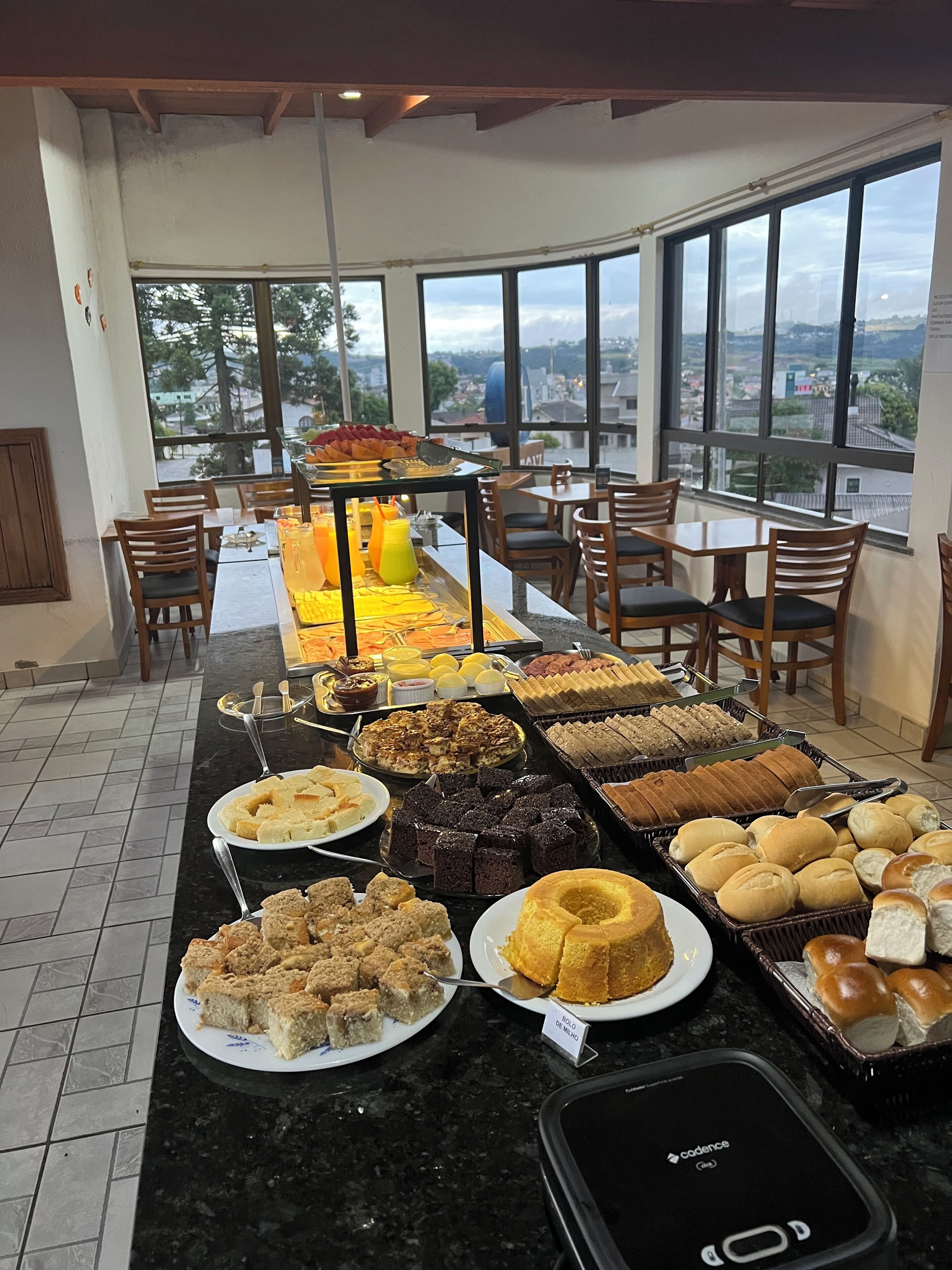 Disposição de buffet com diversos alimentos e um smartphone no balcão.
